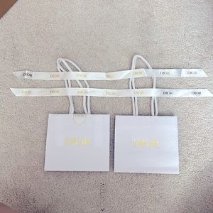 Two mini white and gold Chanel gift bags with 2 ribbons